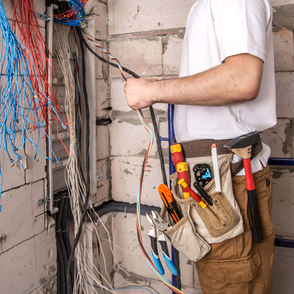 Electrician working near a panel board with wires