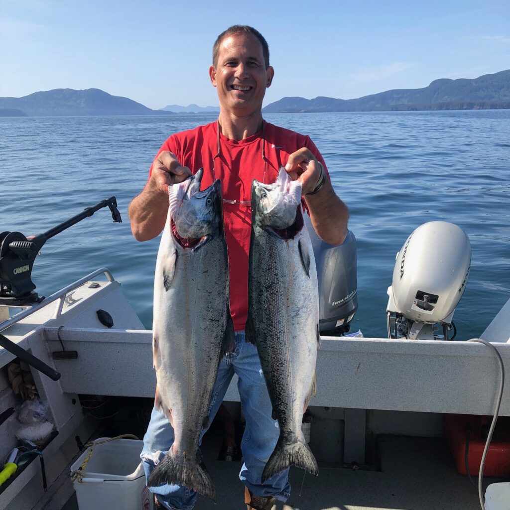 Tim Furgione, Owner-Operator of TLEEF Electric, holding two fish which he caught in Alaska.